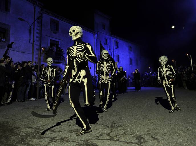 Desfile de personas disfrazadas de esqueletos. Son bailarines realizan la Danza de la Muerte durante una procesión de Semana Santa