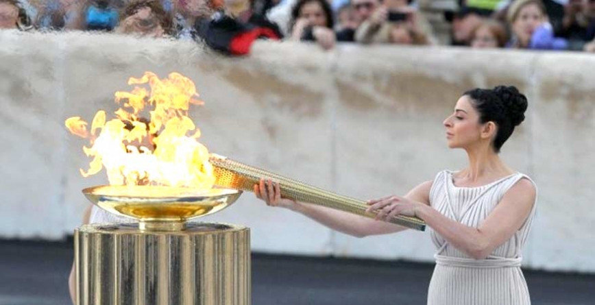 una chica con la antorcha olímpica prendiendo el pebetero