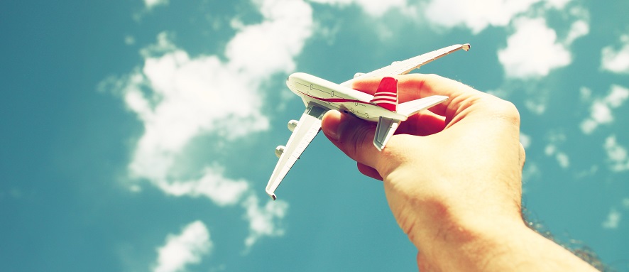 Una mano con un avión de juguete y de fondo se ve el cielo