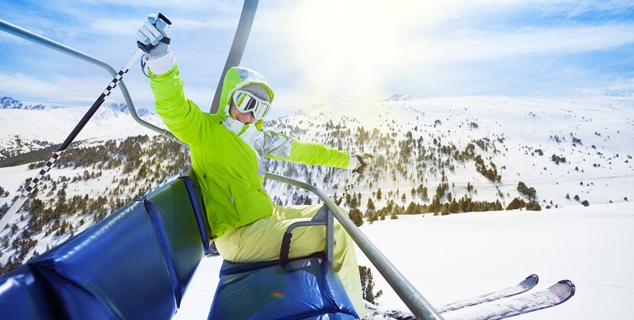 persona sentada en la aerosilla de esqui, de fondo las monañas nevadas
