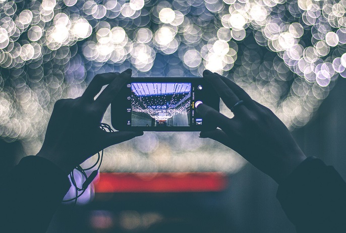 2 manos sosteniendo un móvil para sacar una foto a un techo de luces