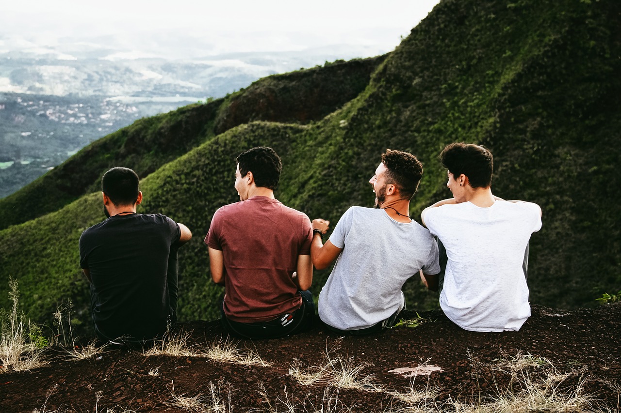 4 chicos de espalda sentados en una montaña