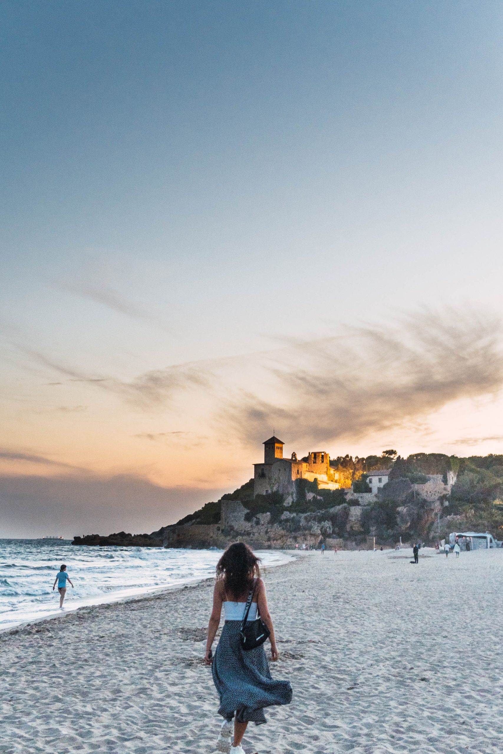 Playa de Tamarit al atardecer con el castillo iluminado sobre la roca
